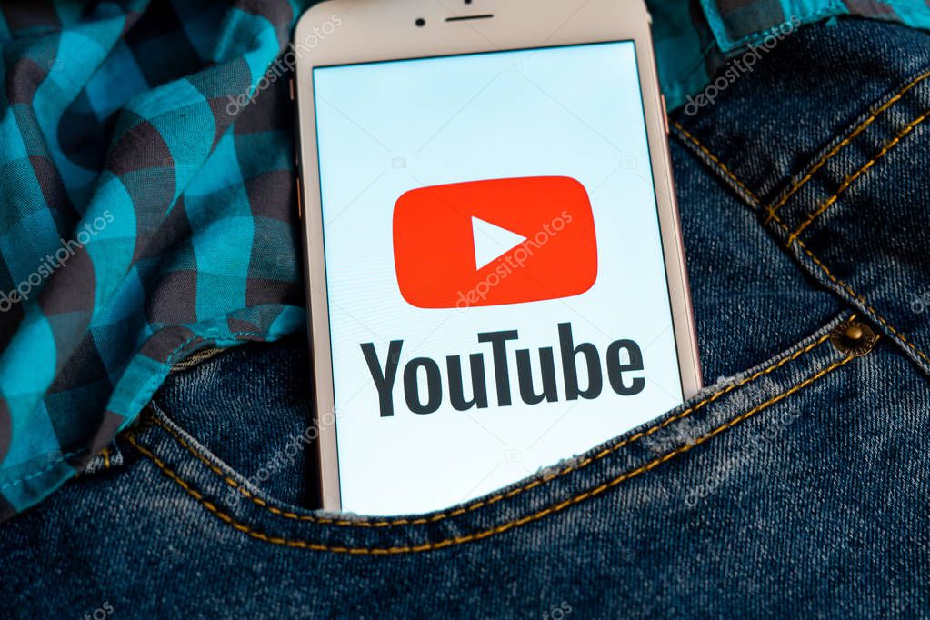Tallinn/Estonia - May 19, 2019: White iPhone with red logo of social media YouTube on the screen. Social media icon. Denim jeans background. Marketing concept or news media illustration.