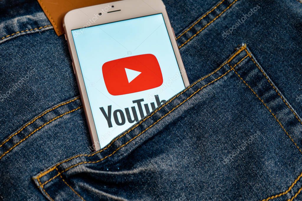 Tallinn/Estonia - May 19, 2019: White iPhone with red logo of social media YouTube on the screen. Social media icon. Denim jeans background. Marketing concept or news media illustration.