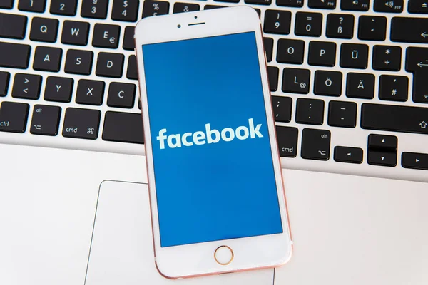 画面上のソーシャルメディアのFacebookのロゴを持つ白いiPhone — ストック写真