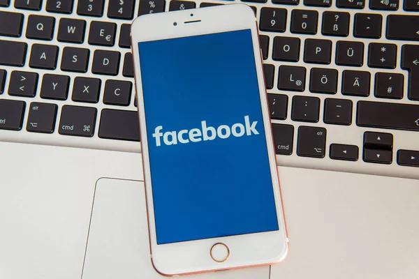画面上のソーシャルメディアのFacebookのロゴを持つ白いiPhone — ストック写真