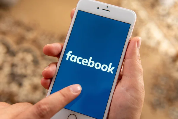 Main féminine avec téléphone Apple avec logo des médias sociaux Facebook — Photo