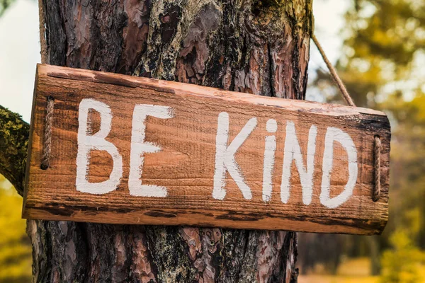 Sinal de motivação de madeira "Seja gentil" no pinheiro — Fotografia de Stock