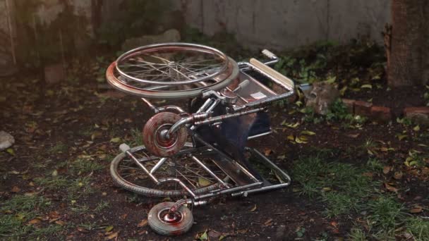 轮椅躺在地上的雨中 一个血淋淋的轮子不停地转动 — 图库视频影像