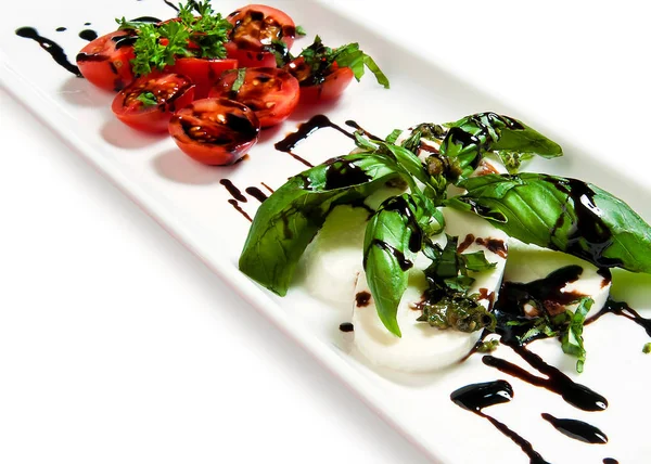 domates sosu ve beyaz arka plan üzerine bir tabak içinde otlar ile