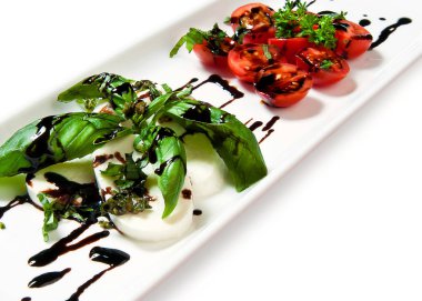 domates sosu ve beyaz arka plan üzerine bir tabak içinde otlar ile