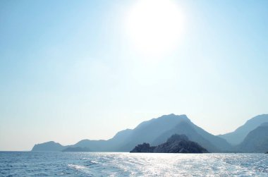 Güneşli gün boyunca denizde dağlar silüeti