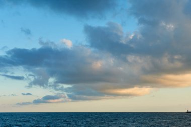 Mavi gökyüzüne karşı denizin üzerinde bulutlar