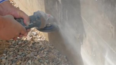Bir işçi açı değirmeni kaldırım taşları kesim için kullanıyor.