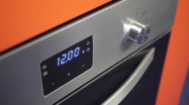 Metalik açma/kapatma düğmesi Ocak fırın. Yakın çekim görünümü. Dijital saat fırın. Ön panel modern metalik fırın, kırmızı göstergeleri, yeni parlak düğmeler. Modern tasarım detayları. Ev aletleri.