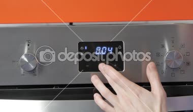Metalik açma/kapatma düğmesi Ocak fırın. Yakın çekim görünümü. Dijital saat fırın. Ön panel modern metalik fırın, kırmızı göstergeleri, yeni parlak düğmeler. Modern tasarım detayları. Ev aletleri.