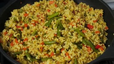 Bulgur yemek: bulgur pilavı. Adam bulgur ile kızarmış sebze karışımları. Sağlıklı taze sebze ile yemek. Bir tavada kızartma sebze.