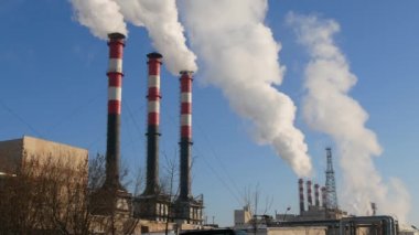 Endüstriyel fabrikalardan gelen hava kirliliği. Tüttüren endüstriyel borular. Beyaz pipolu kırmızı.
