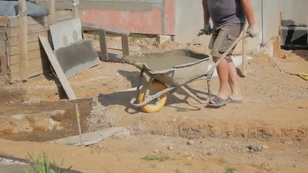 Male Worker Drives Wheelbarrow Full Concrete Trench Foundation — Stock Video