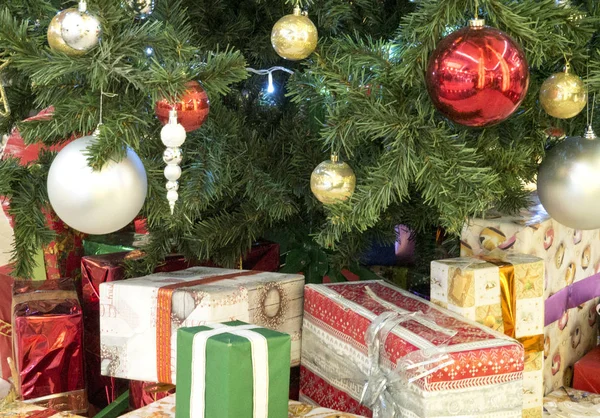 プレゼントとクリスマス ツリーの下のプレゼントを クリスマスの装飾 モミの木の枝に赤と金色のクリスマス ボール — ストック写真