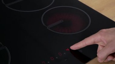 Man tolga el Tunes (düzenler) modern Elektrikli Ocak brülör parlayan parlak kırmızı ısı ile elektrikli pişirme yüzeyi kapanır.