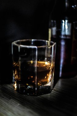 Şişe yanında Whiskey bir bardak, karanlık odada. 