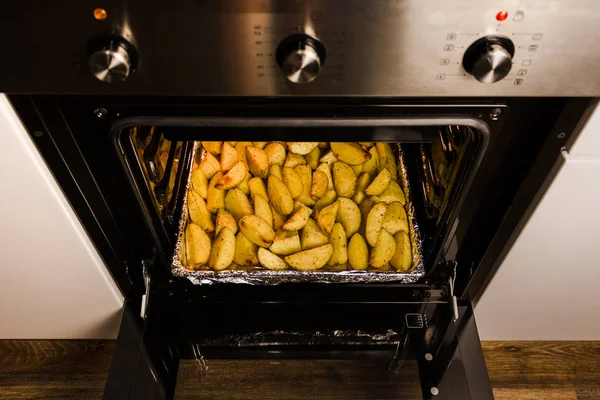 baked potatoes in the oven on a kitchen tray with spices and butter