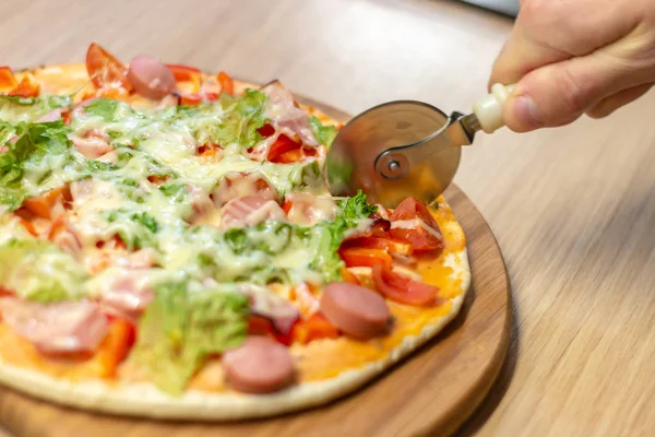 Tangan dekat koki tukang roti dengan seragam putih memotong pizza di dapur, fokus selektif lembut . — Stok Foto