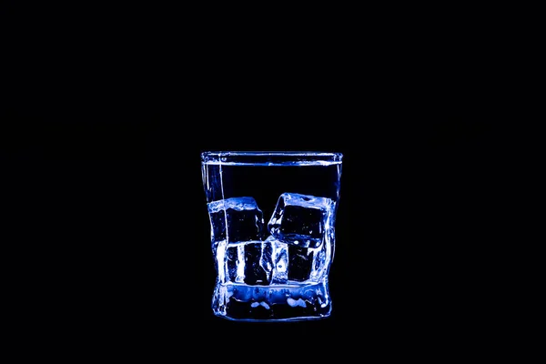 Ijsblokje in een glas blauwe water of drankje. Licht, verfrissing. — Stockfoto