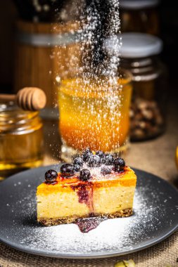 Mavi plaka üzerinde çilek ile cheesecake dilim. Şeker kar. Po