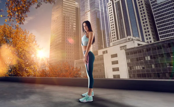 Athlete woman on the city street. Sport tight clothes. Bright su