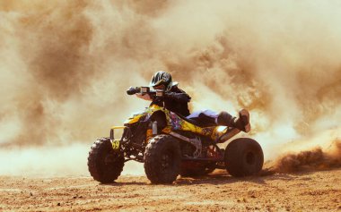 Toz bulutunda dörtlü bisiklet, arka planda kum ocağı. ATV Sürücüsü içeri