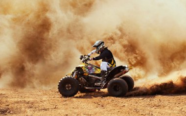 Toz bulutunda dörtlü bisiklet, arka planda kum ocağı. ATV Sürücüsü içeri