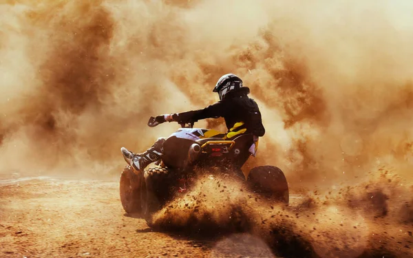 Quad bike in dust cloud, sand quarry on background. ATV Rider in