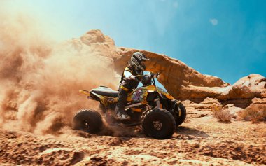 Toz bulutunda dörtlü bisiklet, arka planda kum ocağı. ATV Sürücüsü içeri