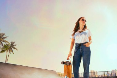 Kaykaycı gün batımında kaykay parkında numaralar yapıyor..