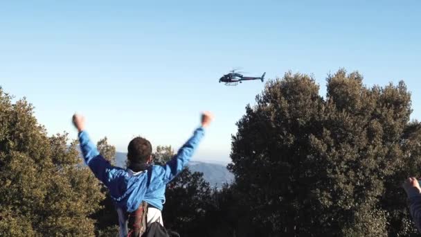 Tipos na montanha acenando com as mãos para o helicóptero que voa sobre eles — Vídeo de Stock