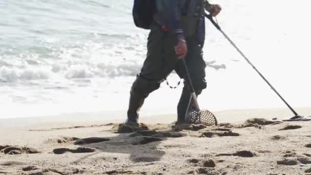 En man med en metalldetektor söker värdefulla saker på stranden — Stockvideo