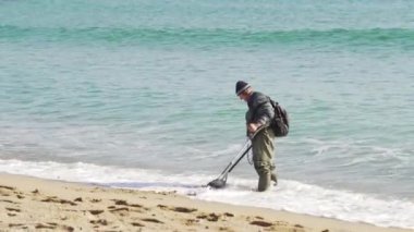 Bir adam bir metal dedektörü ile soğuk hava plaj değerli şeyler arıyor