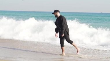 Barcelona'da soğuk ve dalgalı bir deniz kıyısında giysili bir adam duruyor. Sıra dışı