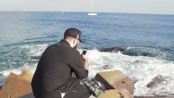 O tipo está a fotografar ondas fortes no cais. — Vídeo de Stock