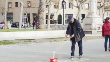 Bir adam büyük sabun köpüğü ana meydanında yapar.