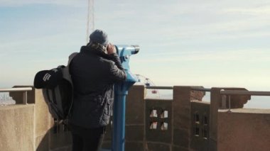 Adam görüş dürbün ile şehrin yükseklikten görünüyor.