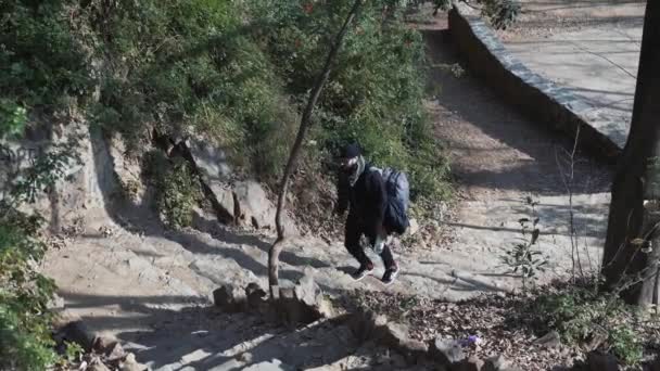 O cara com a mochila sobe as escadas íngremes na floresta — Vídeo de Stock