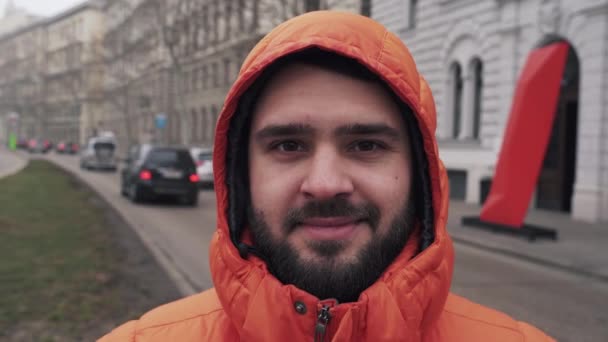 O cara com a barba grossa no capô olha para a câmera e sorri — Vídeo de Stock