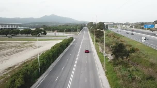 Vista aérea na auto-estrada em Portugal carro vermelho vai em uma estrada livre em torno das árvores — Vídeo de Stock