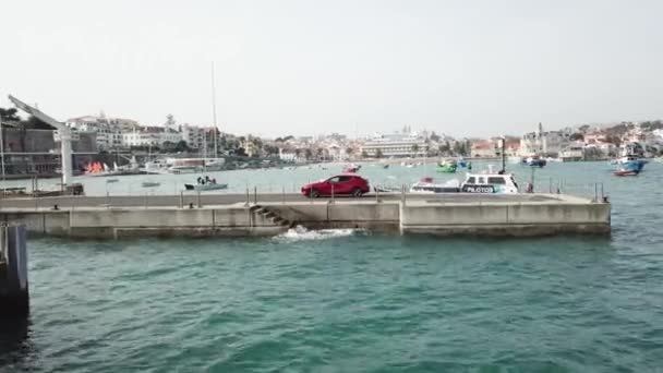 Воздушный беспилотник летает вокруг автомобиля, который стоит на пирсе с яхтами — стоковое видео