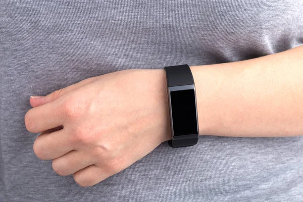 Fitness bracelet on a female hand. The hand is located on the stomach in close-up.