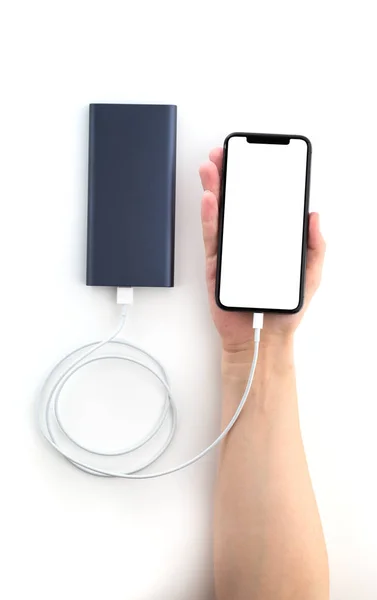 Power bank and smartphone in hand on a white background. The smartphone is charging from the power bank.