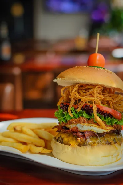 牛肉のパテ ベーコン チェダー チーズ 唐辛子 レタス ピクルス トマトのハンバーガー — ストック写真