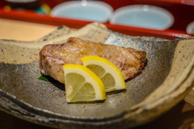 Bir plat üzerinde sunulan limon dilimleri ile ızgara balık