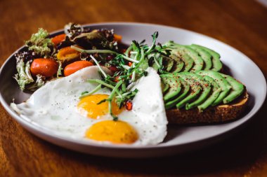 Yumurta ve kiraz domates salatası kadar üst, güneşli tarafı üzerinde avokado ile tost 