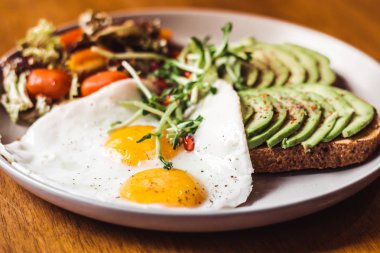 Yumurta ve kiraz domates salatası kadar üst, güneşli tarafı üzerinde avokado ile tost 