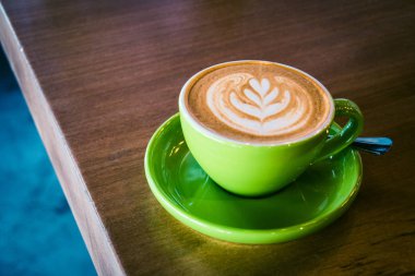 bir yaprak şeklinde foram sanatla bir yeşil Kupası ve uçan daire cappucino