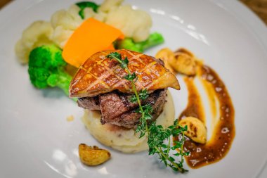 Izgara Bonfile fileto mignon madalyon pastırma ile patates ve mevsimlik Sebze püresi. Kaz ciğeri ile tepesinde ve kırmızı şarap sarımsak confit sos ile.