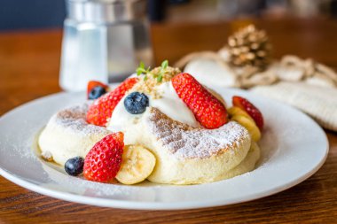 Taze çilek, Berry, muz, krem ve akçaağaç şurubu ile meyve salatası Souffle pancake